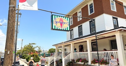 A colorful sign for "Sprinkles Homemade Ice Cream" hangs outside a charming building on a sunny day.