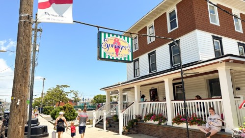 A colorful sign for Springer's Homemade Ice Cream hangs outside a charming building with people enjoying the day.