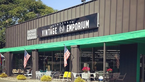 Exterior of Newburgh Vintage Emporium, featuring a sign, colorful outdoor furniture, and American flags.