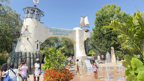 Entrance to Hurricane Harbor water park, featuring a large ship structure and visitors enjoying the sunny day.