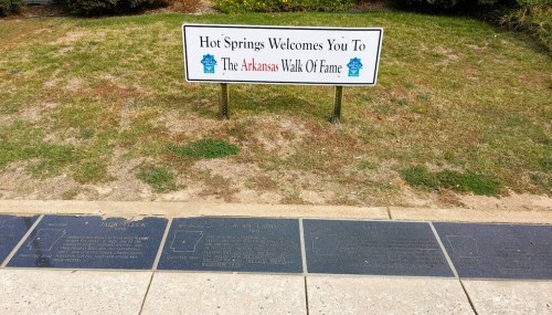 Sign welcoming visitors to Hot Springs and the Arkansas Walk of Fame, with engraved plaques on the ground.