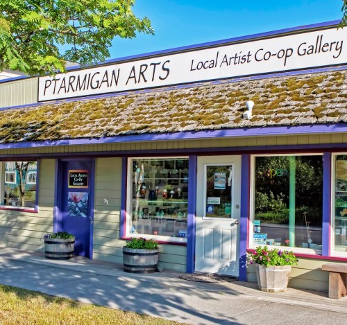 Exterior of Ptarmigan Arts, a local artist co-op gallery, featuring a sign and colorful flower pots.
