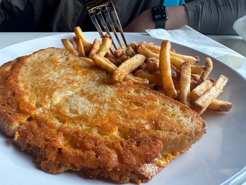 A plate featuring a large, golden-brown breaded cutlet beside a generous serving of crispy French fries.