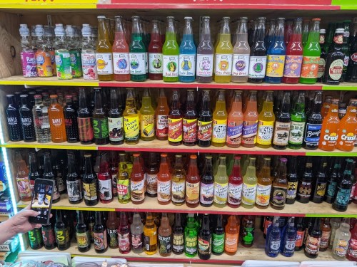 A colorful display of various soda bottles arranged on shelves, showcasing a wide range of flavors and brands.