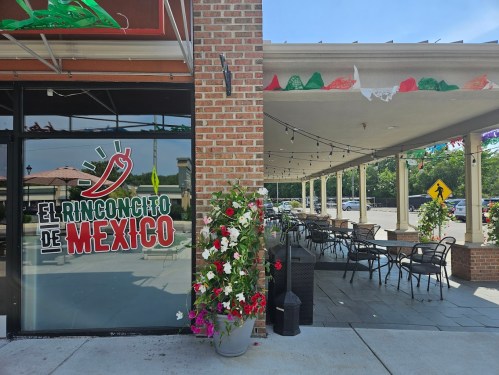 Exterior of El Rinconcito de Mexico restaurant, featuring a patio with chairs and colorful decorations.