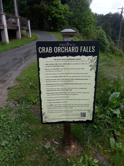 Sign for Crab Orchard Falls with information about the trail, safety tips, and directions, set along a wooded path.