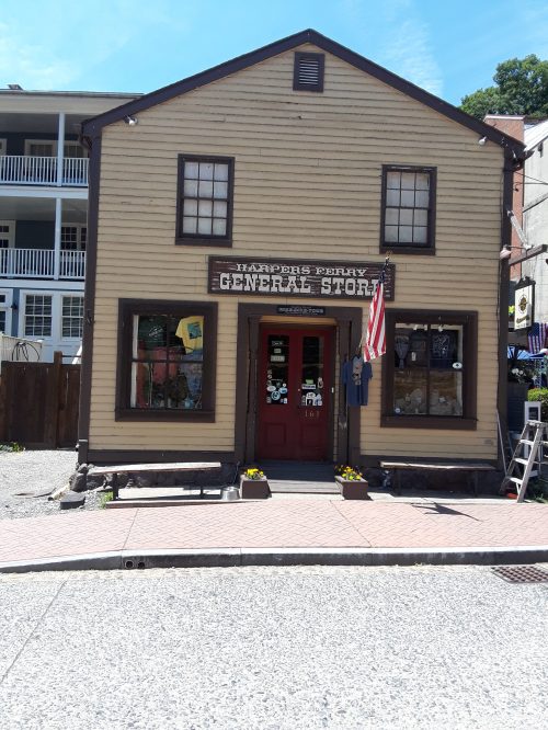 A charming general store with a wooden facade, featuring large windows and an American flag outside.