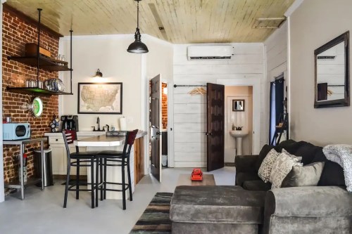 Cozy apartment interior featuring a kitchen, dining area, and living space with exposed brick and modern decor.