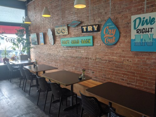 A cozy café interior with brick walls, wooden tables, and colorful signs, creating a welcoming atmosphere.