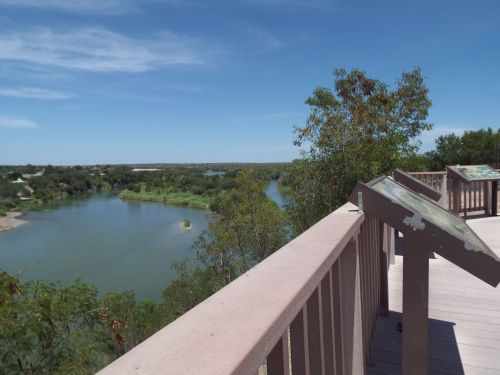 Scenic view from a wooden overlook, featuring a winding river and lush greenery under a clear blue sky.