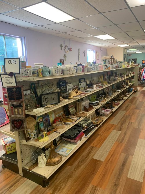 A well-organized thrift store shelf filled with various decorative items, crafts, and household goods.