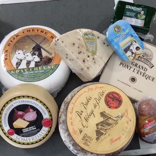 An assortment of various cheeses, including goat cheese, cheddar, and blue cheese, arranged on a gray surface.