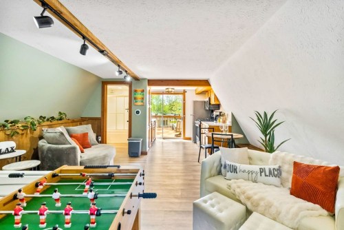 Cozy living space with a foosball table, comfortable seating, and a view of a kitchen and outdoor area.