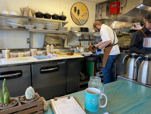 A chef prepares food in a cozy kitchen with various utensils and ingredients on the counter.