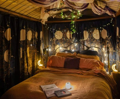 Cozy bedroom with a bed, soft lighting, moon-themed decor, and books on a warm, inviting atmosphere.