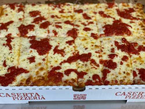 A rectangular pizza with a golden crust, topped with melted cheese and marinara sauce, cut into square slices.