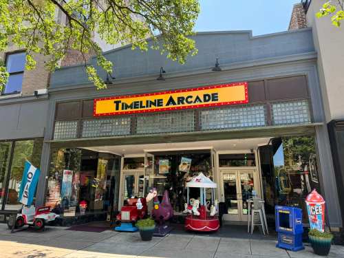 Exterior of Timeline Arcade featuring a bright sign, arcade games, and colorful decorations outside the entrance.