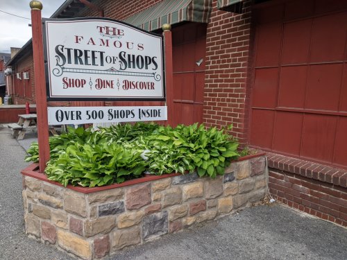 Sign for "The Famous Street of Shops" with greenery and stone base, promoting over 500 shops inside.