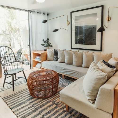 Cozy living room with a sofa, armchair, coffee table, and large windows letting in natural light.