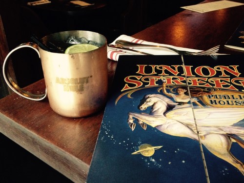 A copper mug with a drink and a lime slice next to a menu for Union Street Public House.