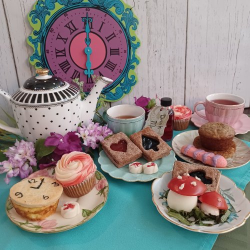 A whimsical tea setup with a polka dot teapot, colorful desserts, and a decorative clock in the background.