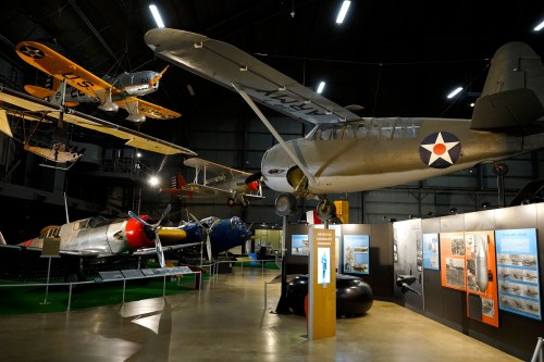 Aviation museum display featuring various vintage aircraft hanging from the ceiling and on the ground.