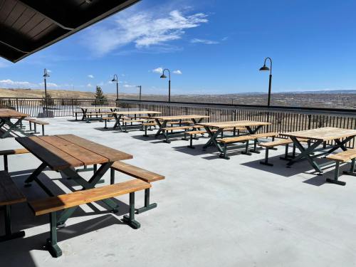 Outdoor seating area with wooden picnic tables and a scenic view under a clear blue sky.