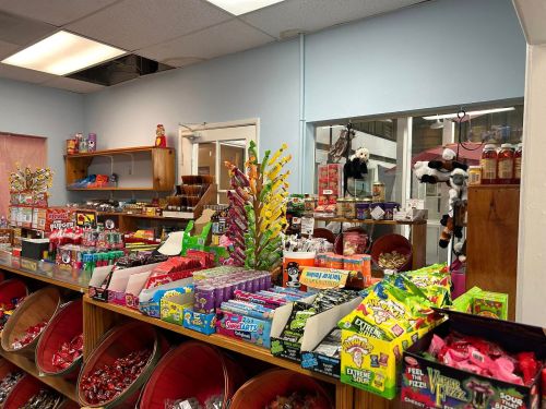 A colorful candy shop display featuring various candies, snacks, and a mirror reflecting the store's interior.