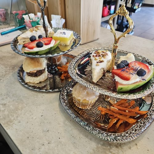 Two tiered trays filled with assorted desserts and snacks, including fruit, cakes, and sweet potato fries.