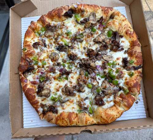 A freshly baked pizza topped with cheese, mushrooms, green peppers, and onions in a cardboard box.