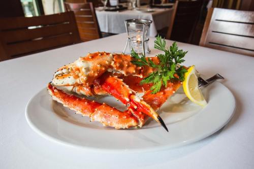 A plate with a large crab leg garnished with parsley and a lemon wedge, set on a white tablecloth in a restaurant.