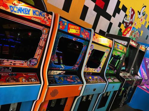 A row of vintage arcade machines, including Donkey Kong and Donkey Kong Junior, against a colorful mural backdrop.