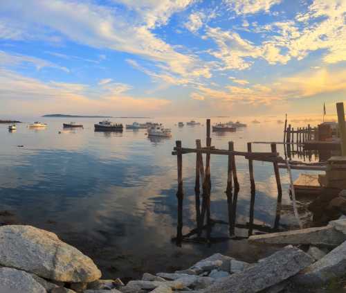 A serene coastal scene at sunset, featuring boats on calm water and a wooden pier against a colorful sky.