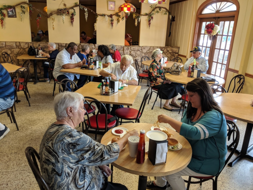 A busy restaurant scene with diners at tables, enjoying meals and chatting in a cozy atmosphere.