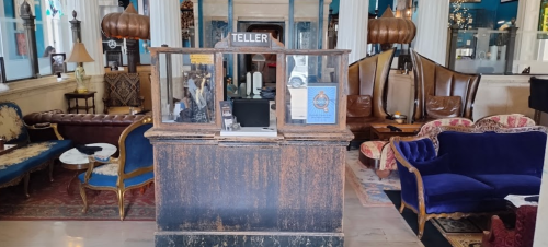 A vintage teller booth in a stylish lobby with elegant seating and decorative elements.
