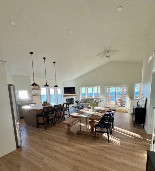 Bright, modern open-concept living space with dining area, kitchen, and large windows overlooking a scenic view.