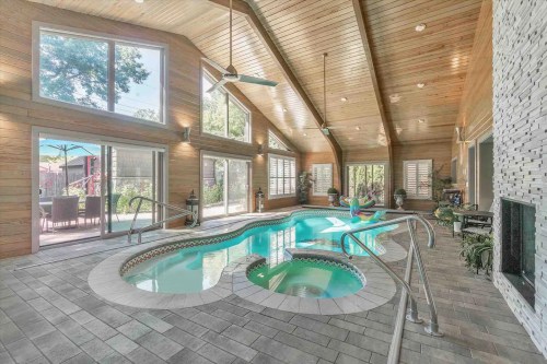 Bright indoor pool area with wooden ceilings, large windows, and a cozy seating space.