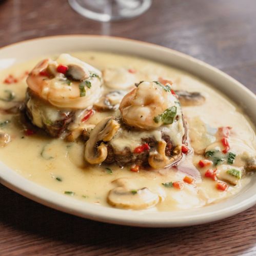 A plate of shrimp and mushrooms in a creamy sauce, garnished with red peppers and herbs.