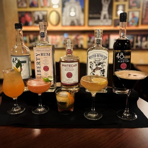 A variety of colorful cocktails and bottles of spirits arranged on a bar counter.