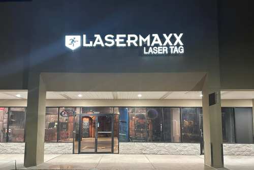 Exterior of Lasermaxx Laser Tag building at night, featuring a bright sign and large glass entrance.