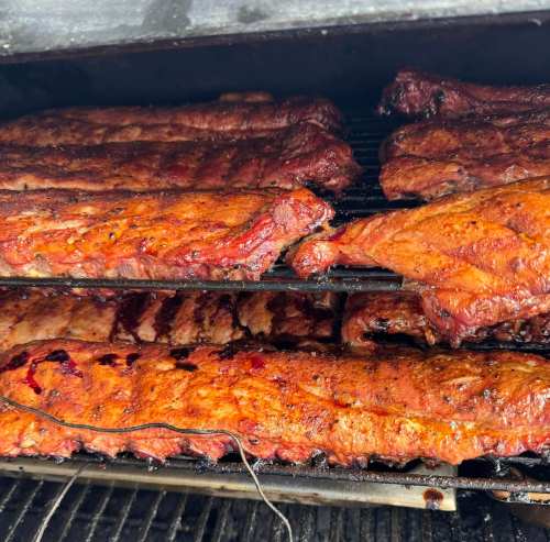 Close-up of smoked ribs on a grill, showcasing a rich, caramelized exterior and juicy texture.