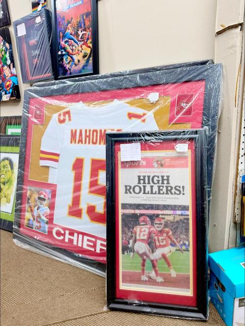 Framed Patrick Mahomes jersey and a newspaper clipping titled "HIGH ROLLERS!" displayed in a store.