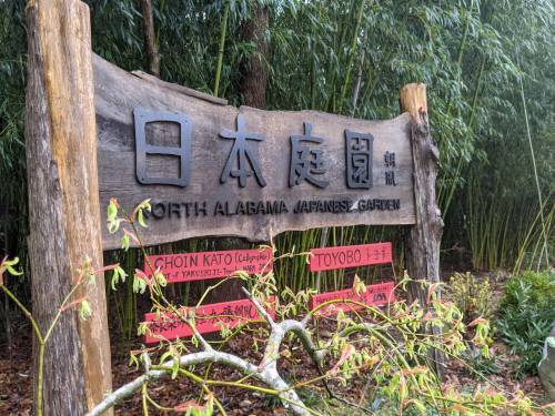 Sign for North Alabama Japanese Garden, featuring wooden structure and bamboo in the background.