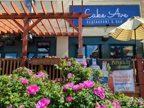 Exterior of Lake Ave Restaurant & Bar with flowers in the foreground and a sign advertising brunch specials.