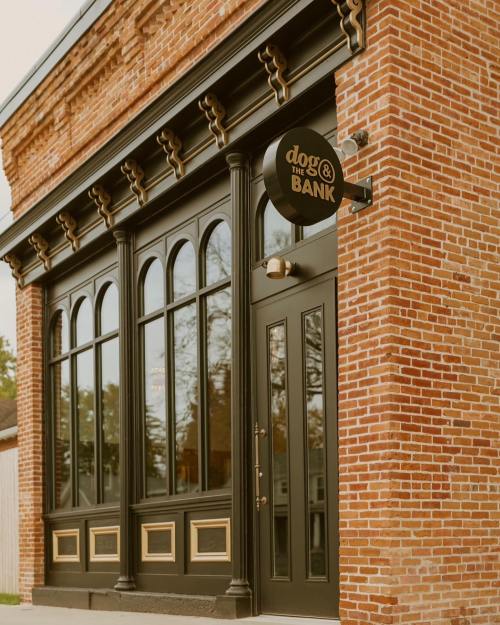 Exterior of a brick building featuring large arched windows and a sign that reads "dog & the BANK."