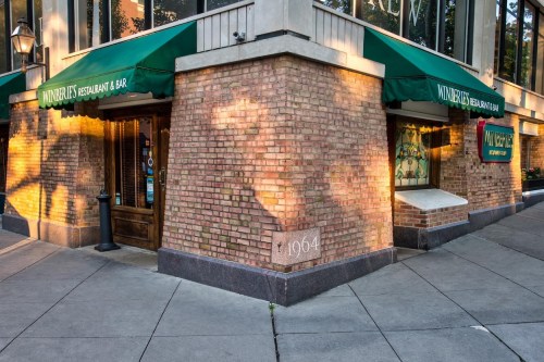 Exterior of a brick restaurant with green awnings, featuring a corner entrance and a sign that reads "Wunderbar."