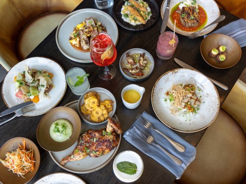 A vibrant table spread featuring various dishes, drinks, and garnishes, showcasing a colorful culinary experience.