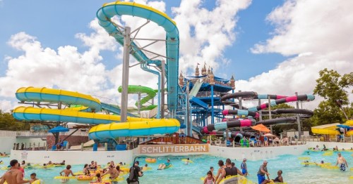 A vibrant water park with colorful slides, a lazy river, and people enjoying the water on a sunny day.