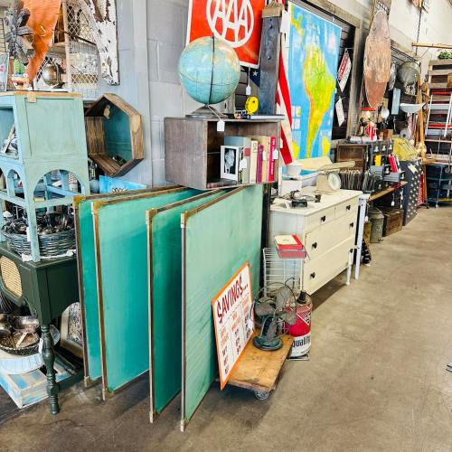 A vintage shop display featuring furniture, globes, and various antiques against a gray wall.
