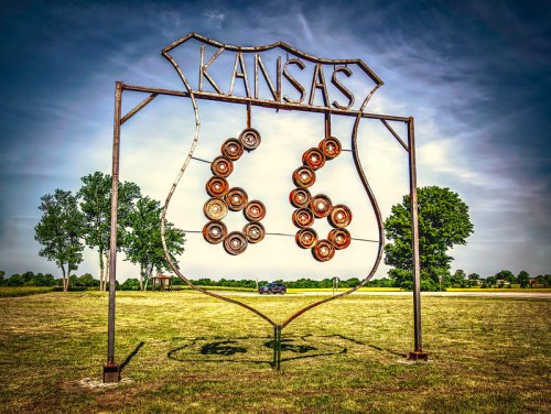 A large metal sign reading "Kansas 66" stands in a grassy area under a cloudy sky.